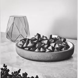 a bowl of cut up fruit sits next to a vase on a table