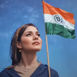 a woman holding up an indian flag with a blue sky behind her