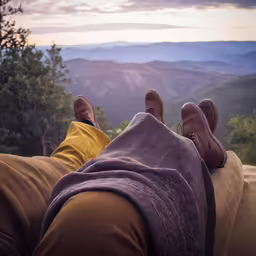 man lying down on the ground looking out over a valley