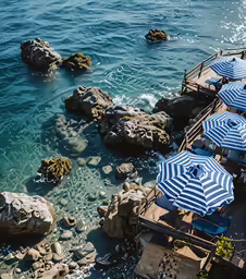 a couple of beach chairs and umbrellas sitting on the side of the water