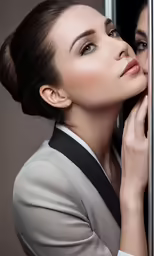 the woman in a grey suit is leaning up against a wall