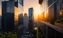 the sun sets behind some very tall buildings