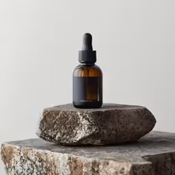 an open glass bottle sits on top of a stone sculpture