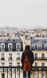 a woman that is standing on a railing looking over the city