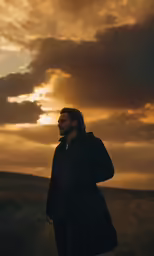 a man standing on a dirt road during sunset