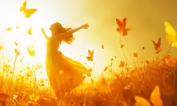 a woman is walking in the grass with butterflies
