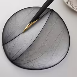 a black and gold plate with a knife on top of it