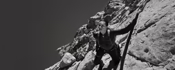 man standing on the side of a mountain holding onto his rope