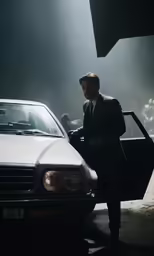 man in suit and goggles standing by an mercedes car