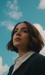 a young woman wearing a black jacket is looking upward into the distance