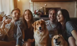 a group of people sitting together with their two dogs