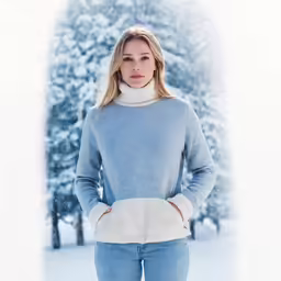 a woman standing in snow wearing knitted gloves
