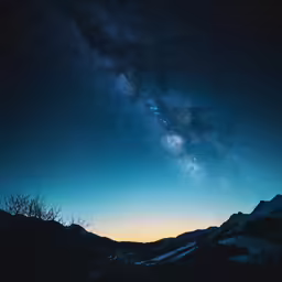 the starr filled sky over a snowy mountain range