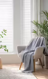 a large grey blanket sitting next to a chair and a window