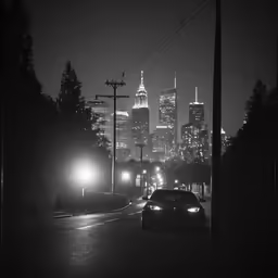 a black and white photo of cars driving down a city street