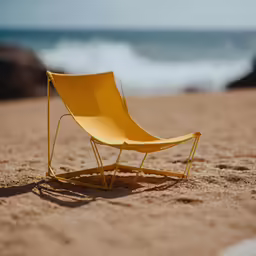 the yellow chair is on the sand near the ocean