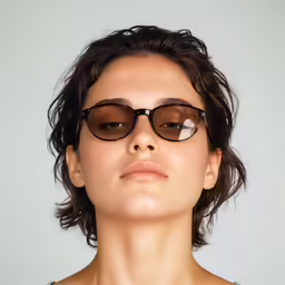 a woman is standing in front of a wall with glasses on