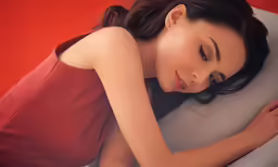 a woman laying down on a pillow while hugging her head
