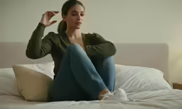 a woman sitting on top of a bed while making an obscene face