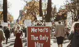 a woman standing in the middle of a street holding a sign