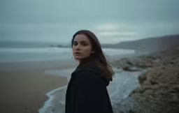 a young woman standing on top of a sandy beach