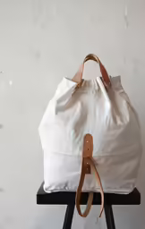 a white canvas bag sitting on a stool