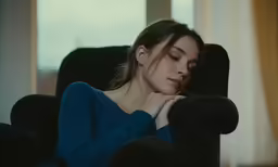a woman sitting down looking sleepy in a chair