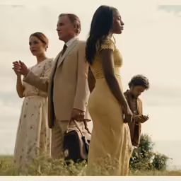 a group of people standing next to each other on a grass field