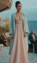 the model in a long dress is standing on the beach