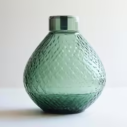 the glass bottle is sitting on a white surface