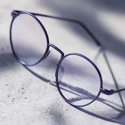 a blue frame sunglasses with one clear lens on a gray surface