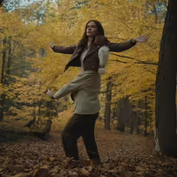 a woman is playing in the leaves of a forest