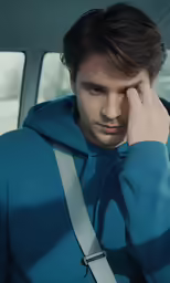 a man holding his head in a car