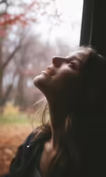 a woman stares out the window on a misty day