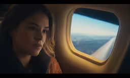 a beautiful young woman sitting on an airplane seat in front of an airplane window