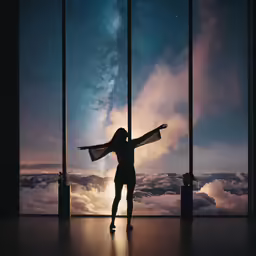 a girl is standing with her arms spread out looking up into the sky