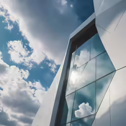 a photo of the exterior of a tall building with clouds reflected in it