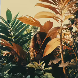 a woman standing next to green plants with a sky background