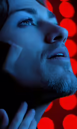 a man looks up into the distance and is touching his ear