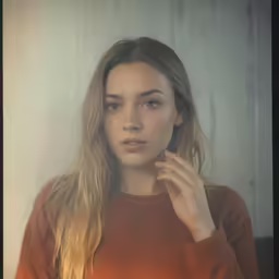 a woman standing in front of a wall wearing a sweater