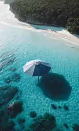 an overhead view of a beach with a large blue umbrella on it