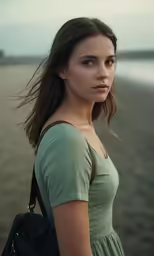 a girl in a green dress is standing on the beach
