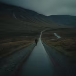 a lone man walks alone down the middle of a road