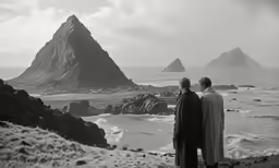 two people standing in front of a rocky ocean shore