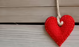 red decorative heart hanging on wood planks