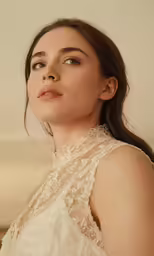 a woman wearing a white dress and pearls on her neck