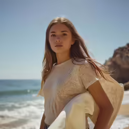 a young woman carrying her surfboard along the beach