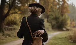 woman walking down dirt path carrying wicker bag