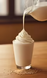 a glass of milk being poured into a beverage cup