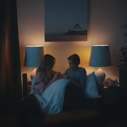 two young children sitting on a bed under a picture